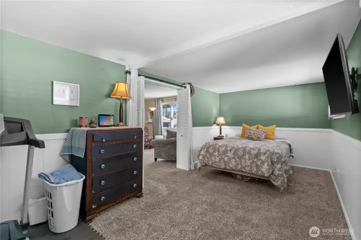 The primary bedroom is located off the living room and features charming wainscotting.