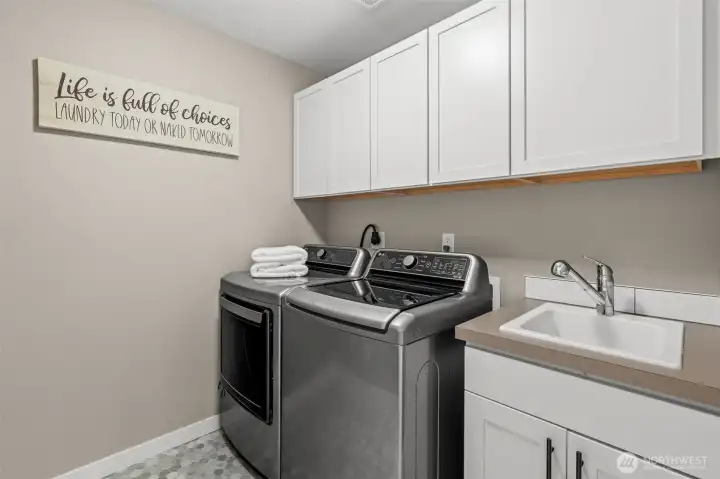 A bright and spacious laundry suite featuring durable tiled flooring and extensive cabinetry for effortless organization