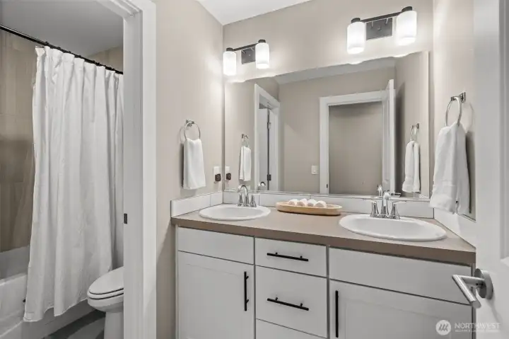 With spa-like features, this shared bathroom located on the upper floor features a dual vanity and floor to ceiling tiling in the shower.