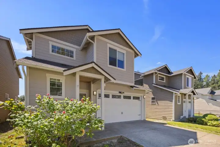 Angled exterior view highlighting the covered entry, modern exterior finishes, and low-maintenance front landscaping.