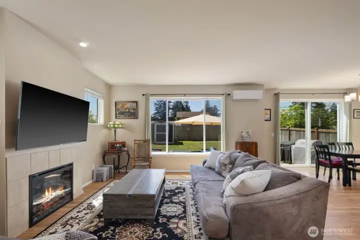 Open living room with large windows, recessed lighting, and an electric fireplace centered along the main wall.