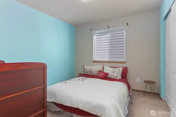 Upstairs bedroom with natural light, neutral carpet, and closet storage.