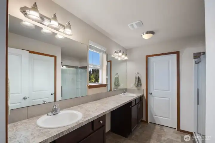 Primary bathroom with dual-sink vanity, oversized mirror, and abundant counter space.