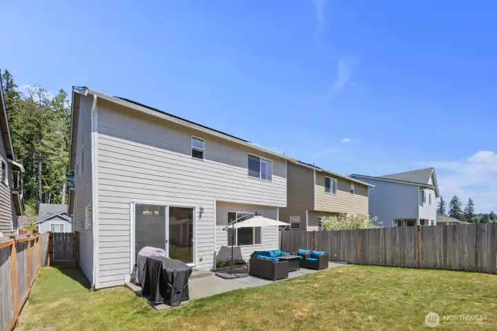 Fully fenced backyard with patio space, open lawn, and room for outdoor entertaining.