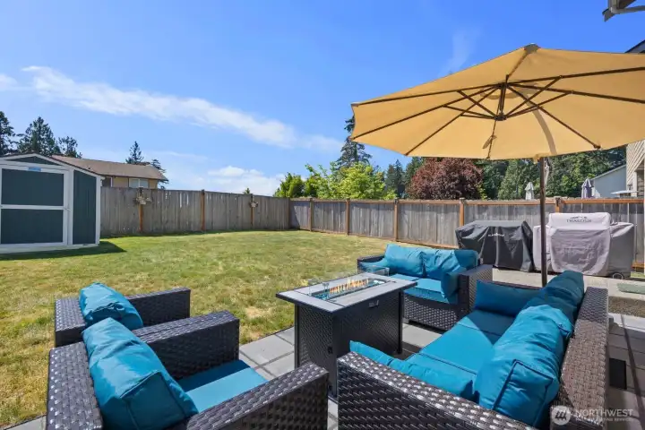 Backyard entertaining space with patio seating, open lawn, and fully fenced yard.