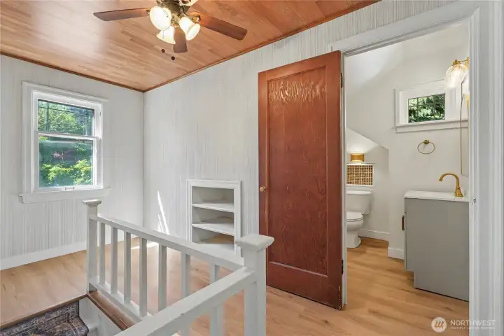 View of the upper stair landing with half bath in the background.