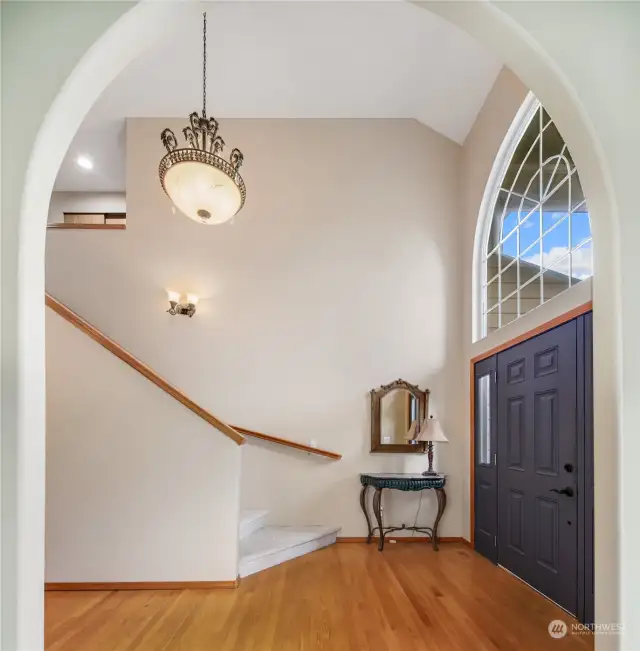 Two story open interior entry with beautiful oak hardwood floors and picture niche