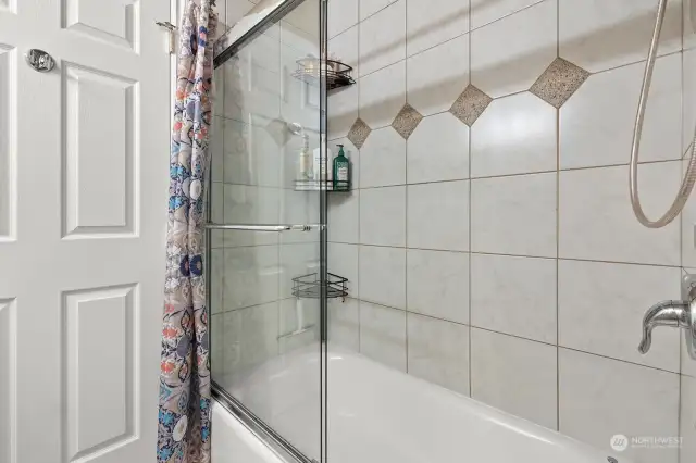 Tiled shower & tub has glass sliding door