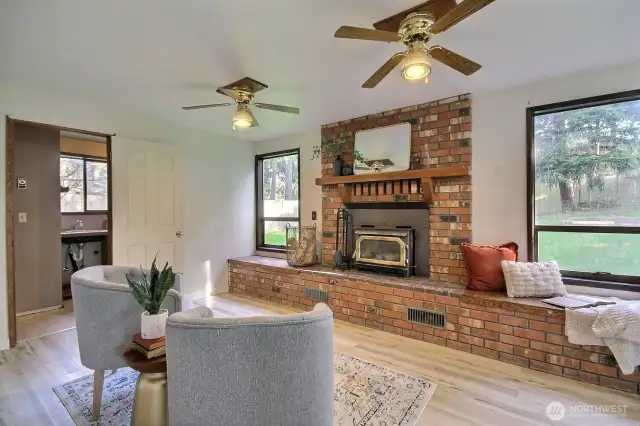The open-concept living and dining areas flow seamlessly into a cozy family room, complete with brick fireplace and woodstove insert.