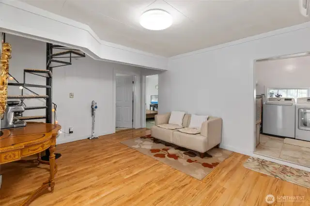 The open space below the stairs to the upper level. The primary bedroom is through the open door straight ahead, with a 2nd bedroom in the adjacent door to the left.