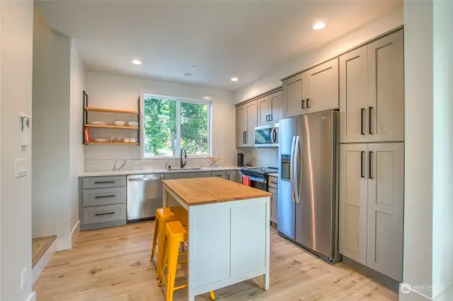 The kitchen features sleek quartz countertops and a central island topped with a butcher block surface, perfect for casual dining.