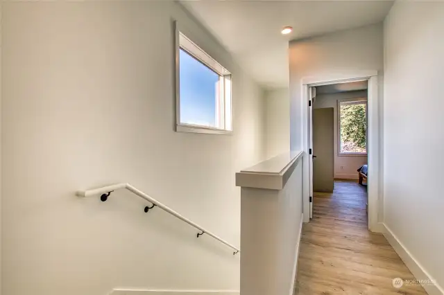 The hallway connects two upstairs ensuite bedrooms, with a laundry area conveniently located at the top of the stairwell.