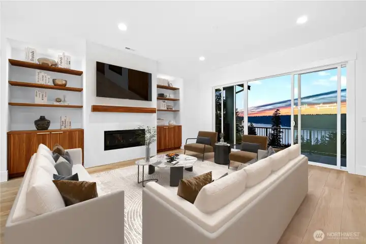 Spacious living room featuring a gas fireplace with plenty of built-in shelving and storage, perfect for entertaining or everyday living. Enjoy sweeping Lake Sammamish views through large sliding glass doors that open to the main-level wraparound deck.
