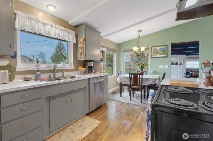 This view shows Light and bright refreshed kitchen with dining area and box beam ceilings. Doorway to the left leads to family room and garage with an exterior door.