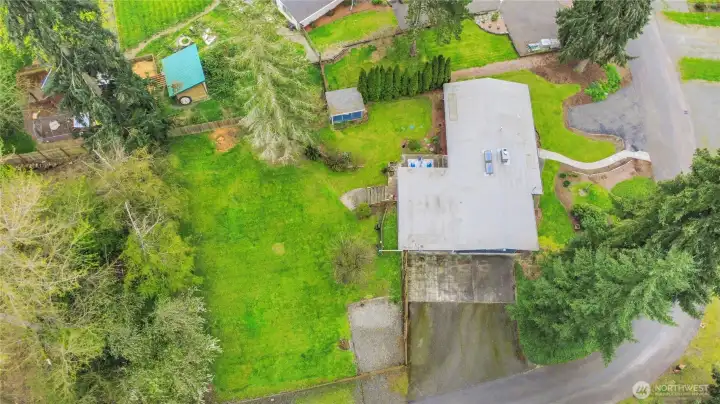 This aerial shot shows huge drive way, RV parking behind fence, outdoor storage shed and in front of home is guest parking.Property goes back to tree line.