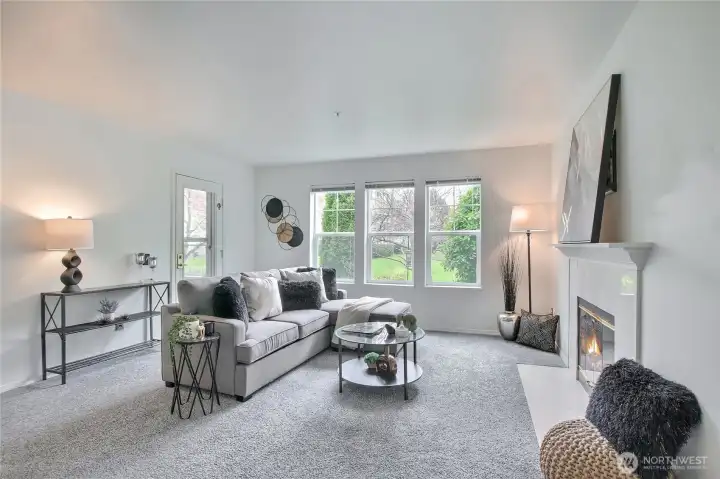 Large living area with wood burning fireplace, (App added flame), and door to patio.