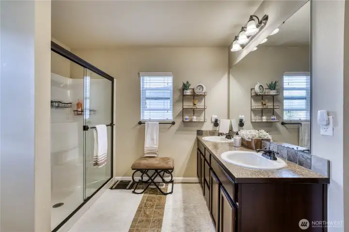 Primary bath with dual vanities and walk in shower with sliding glass door.
