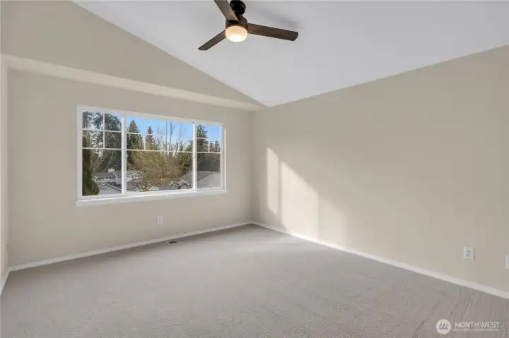 Vaulted ceilings and a large window complement the primary bedroom.