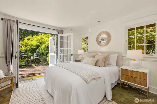 The primary suite’s cozy sleeping space opens to a paved patio with glorious views of the landscaping and pond.