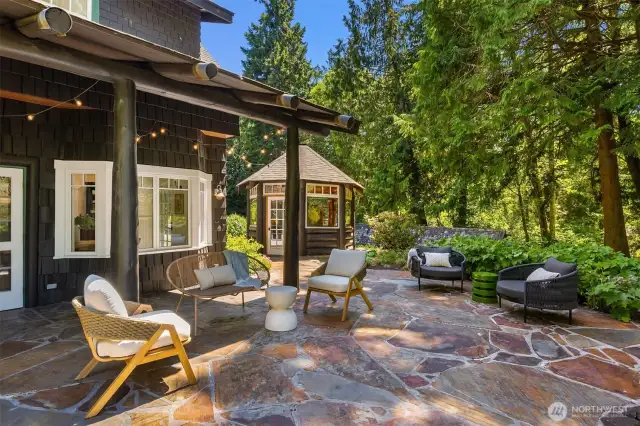 This fabulous patio just off the kitchen and dining area offers covered space (for your grill or for rainy days) as well as a large uncovered space. The pizza gazebo is seen in the distance. Here, this patio is shaded in the afternoon by a set of stunning fir trees.