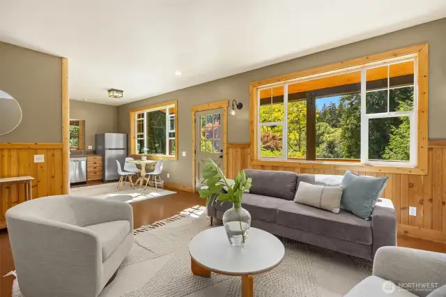 Here, we see a view from the living room over towards the kitchen. The interior features warm, rustic finishes that lend it a truly cozy vibe, but the beadboard and trim could certainly be painted for a more modern feel.