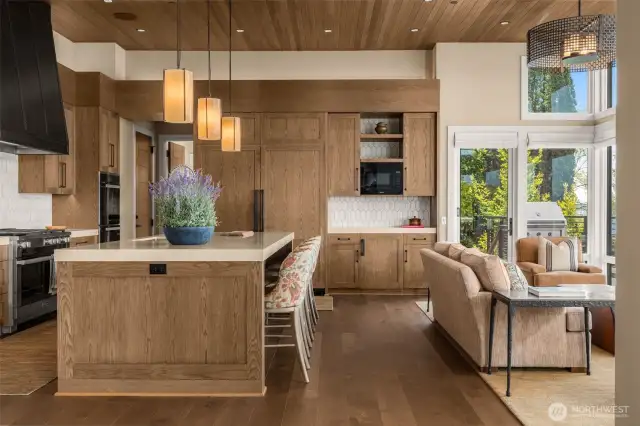 Island eating bar and casual sitting area with outdoor kitchen & prep space beyond.