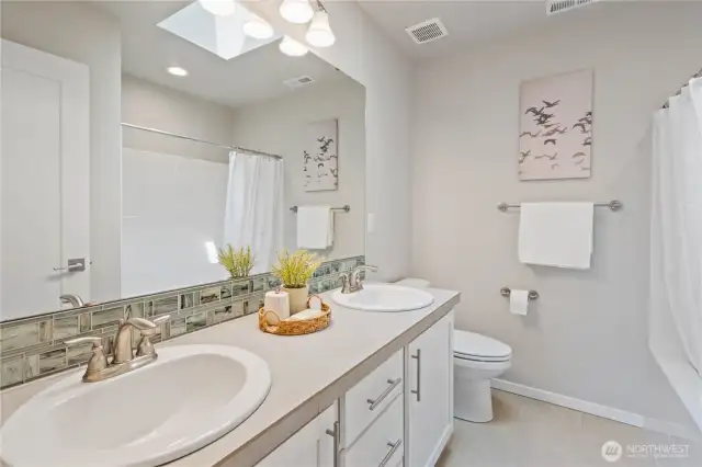 Central to all three bedrooms is the full guest bathroom with dual vanity sinks, tiled flooring, tiled backsplash and a bonus skylight for even more natural light.