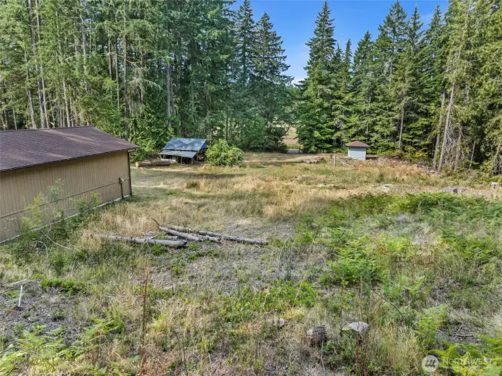 West facing view. Shop (left), carport, outbuilding with pressure tank (right) and Mace Lake across the street.
