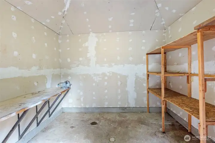 Interior of outbuilding with additional storage, shelving and the pressure tank.