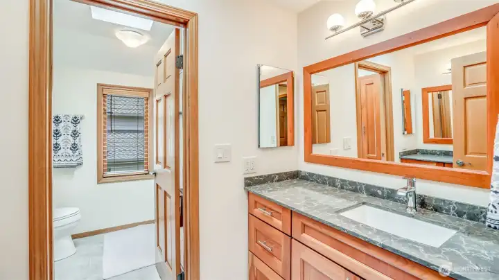 Updated bath featuring sleek finishes, ample storage, and a private water closet.
