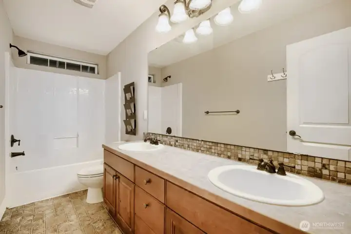 Full bath with dual sink vanity and tub/shower combo.