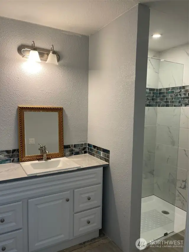 New vanity, titled shower and toilet in garage bathroom.