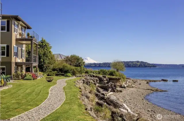 Relax and enjoy the scenic view of Rich Passage from the comfort of Adirondack chairs, creating a perfect spot to unwind and take in the natural beauty of the surroundings.
