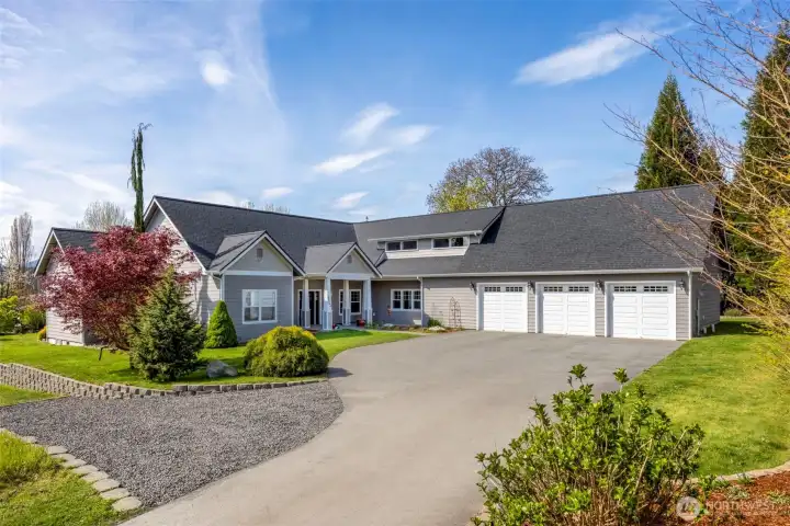 Front view of house with three car garage, RV gravel parking pad & landscaping.