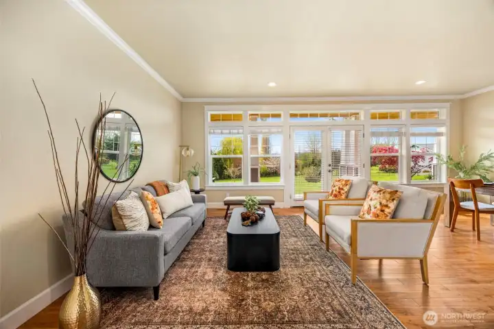 Living room just off the entryway, filled with natural light from panoramic windows and French doors that create a bright, open feel.