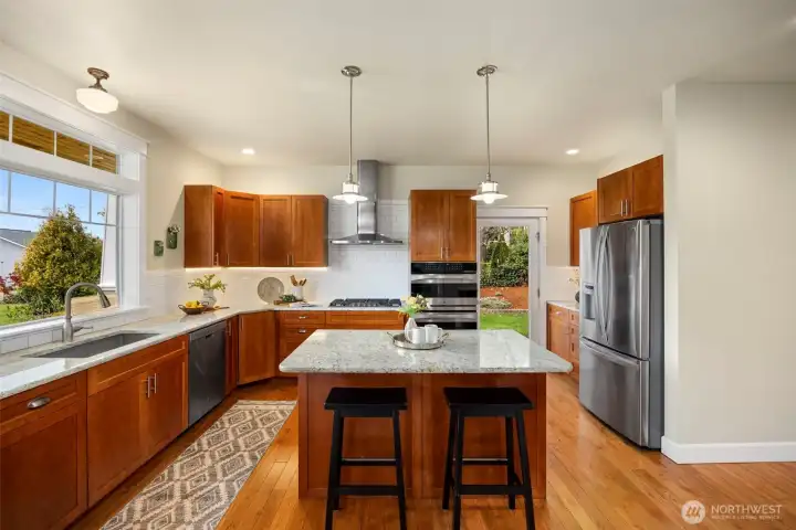 Kitchen is beautifully appointed with granite countertops, shaker cabinetry, white subway tile, a gas range, and two spacious pantries.
