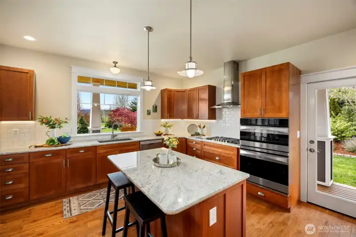 Kitchen is beautifully appointed with granite countertops, shaker cabinetry, white subway tile, a gas range, and two spacious pantries.
