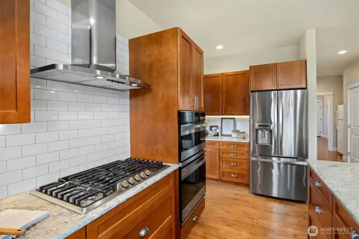Kitchen is beautifully appointed with granite countertops, shaker cabinetry, white subway tile, a gas range, and two spacious pantries.