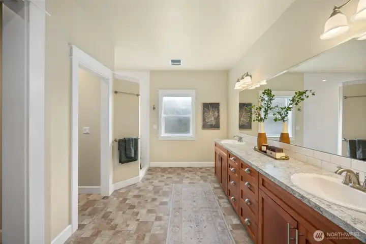 Primary bathroom with dual sinks, walk-in closet and large subway title  walk-in shower.