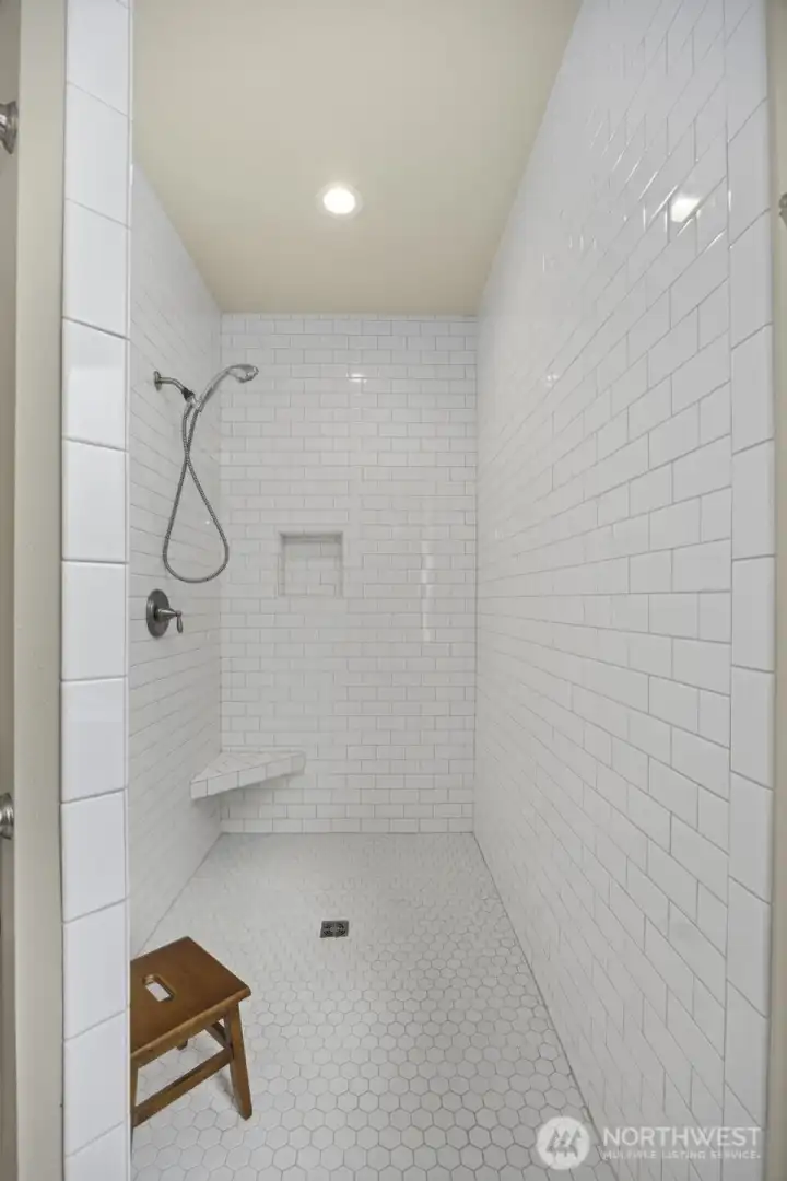 Large walk-in shower, with white subway title in primary bathroom.