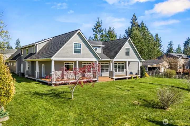 Back view of the house with covered porch and large yard.