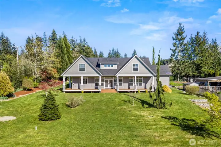 Back view of the house with covered porch and large yard.