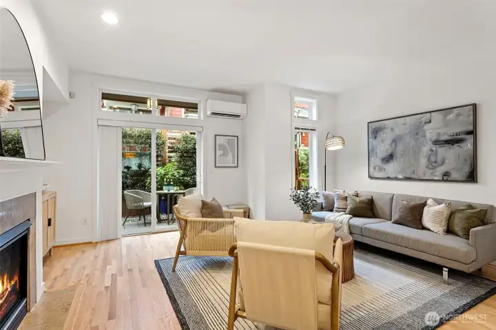 The spacious living room features refinished hardwood floors, a cozy gas fireplace and a wall of windows letting in ample natural light.