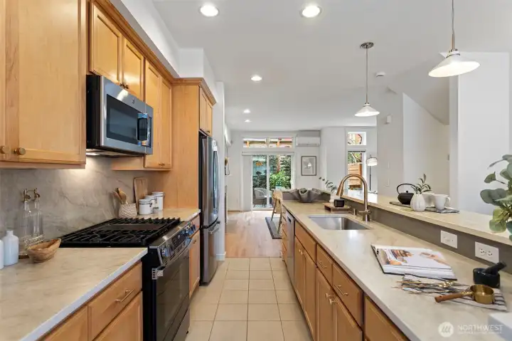 The extra long galley kitchen features custom maple cabinets with new gold hardware.  Enjoy West Elm pendant lighting over the bar.