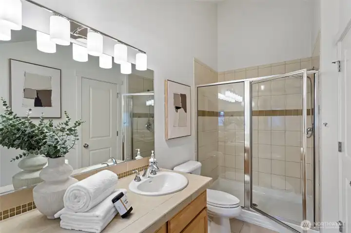 The primary bathroom features an extra large shower with tile surround, a double vanity and new modern light fixture.