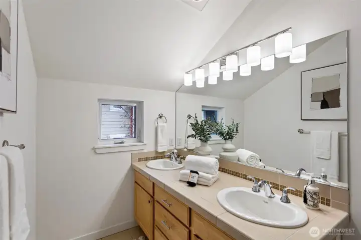 The primary bathroom features a double sink vanity with maple cabinetry.  A modern light fixture and new drawer pulls were just added.