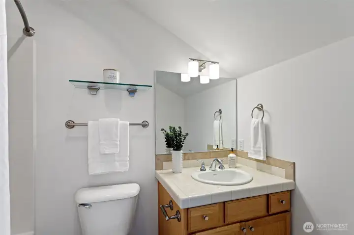 2nd primary suite bathroom features a single sink vanity and bathtub / shower.  The light fixture and hardware were recently added.