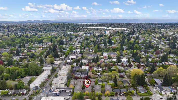 Drone shot looking west looking at Green Lake and Roosevelt light rail station.  In the distance you can see Puget Sound and the Olympic mountains.