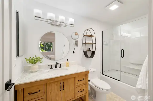 Remodeled bath with new vanity, counter top, light and plumbing fixtures, shower/tub surround and shower door.