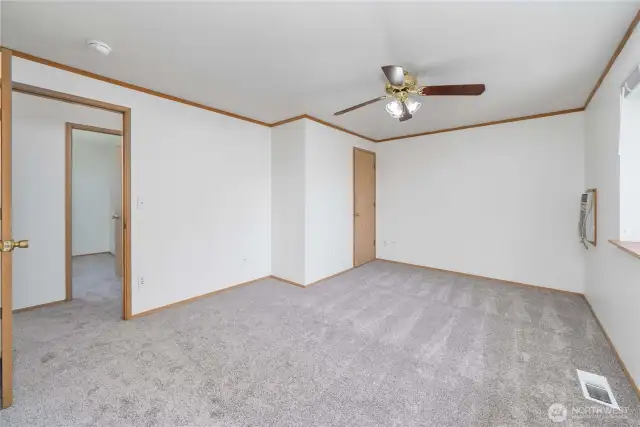 Primary suite with walk-in closet, ceiling fan, a wall A/C unit & an attached bath.